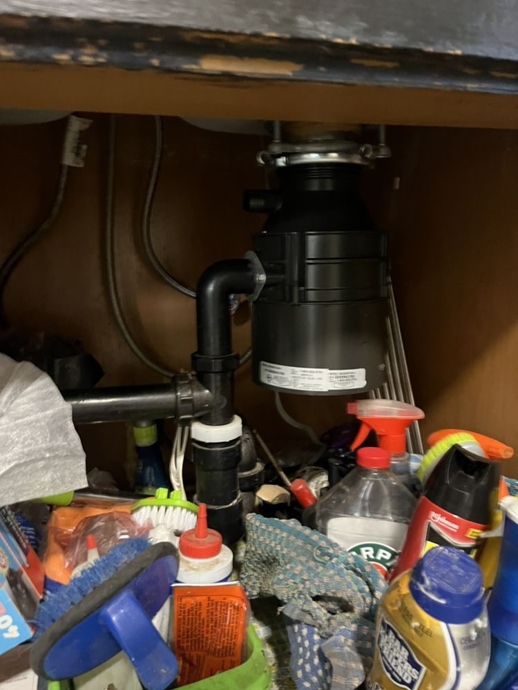 New disposal installed in cluttered under-sink space
